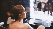 a woman is sitting in front of a mirror and looking at herself