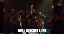 a man in a red coat is standing in front of a group of people with burn butcher burn written on the bottom