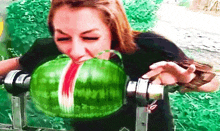 a woman is eating a large watermelon with a machine .