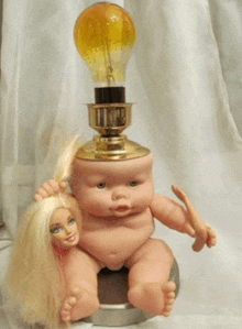 a barbie doll is sitting next to a baby doll with a light bulb on top of his head