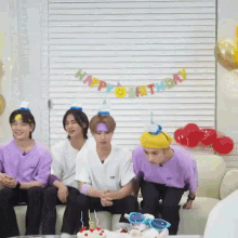 a group of young men are sitting on a couch with a birthday cake and a happy birthday banner behind them