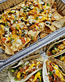 a tray of nachos and tacos with cheese and vegetables