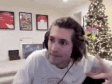 a man wearing headphones is sitting in front of a christmas tree .