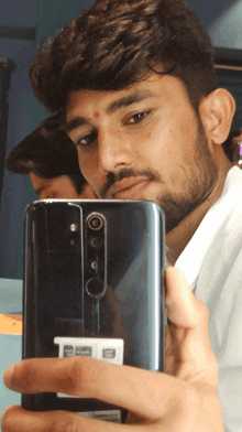 a man taking a selfie with a phone that has a sticker on it that says ' redmi '