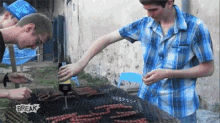 a group of young men are cooking sausages on a grill with a sign that says break on it .