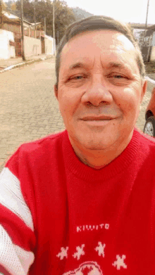 a man wearing a red and white sweater that says kikoito smiles for the camera