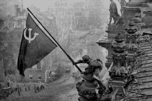 a black and white photo of a man raising a flag