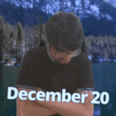 a man with his arms crossed stands in front of a lake with the date december 20