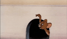 a cartoon mouse is peeking out of a hole in a wall .