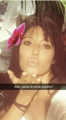 a woman blowing a kiss with a flower in her hair and a caption that says " aller garde le smile bouffon "