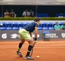 a man is holding a tennis racquet on a tennis court in front of a sign that says mexico city open