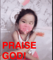 a little girl with pink paint on her face and the words praise god in red