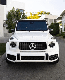 a white mercedes with a black grille is parked in front of a white building