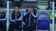 a man covering his face while sitting in a stadium with a sign that says ' israeli ' on it