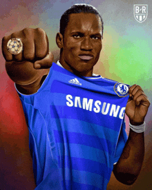 a soccer player wearing a blue samsung jersey holds up his fist