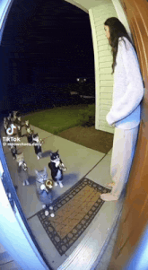 a woman is standing in front of a door with a group of cats playing trumpets
