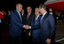 a man in a suit shakes hands with another man in front of an airplane that says cnn