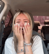 a woman sitting in a car with her hands on her face