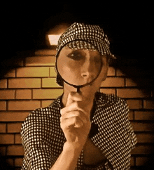 a woman in a hat is holding a magnifying glass to her face .