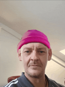 a man wearing a pink beanie and a grey adidas shirt