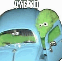 a green stuffed animal is sitting in a blue car with the words `` aye yo '' written on it .