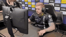 a man wearing headphones is sitting in front of a computer monitor with intel logos on the wall behind him