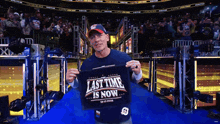 a man is holding up a shirt that says last time is now
