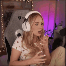 a woman wearing headphones and a shirt with strawberries on it sits in a gaming chair