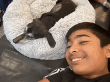 a young boy is smiling next to a dog in a dog bed