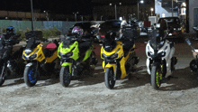 a row of motorcycles are parked in a dirt lot