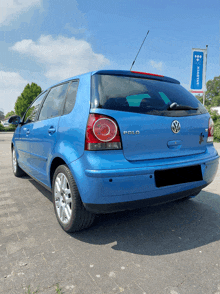 a blue volkswagen polo is parked in front of a sign that says ' unisex '