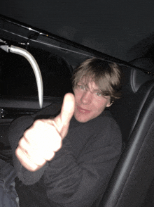 a man in a car giving a thumbs up sign