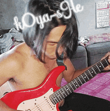 a shirtless man is playing a red guitar with koya-s-gle written on his head