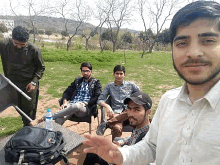 a group of men are posing for a picture in a park with a backpack that says ' columbia ' on it