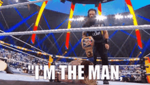 a man is standing in a wrestling ring holding a championship belt and saying `` i 'm the man . ''