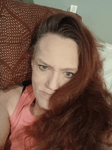 a woman with red hair is laying on a bed with a pillow that has a label on it that says ' cotton '