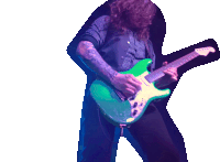 a man with long hair is playing a green guitar on a stage