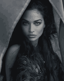 a black and white photo of a woman with feathers on her hair