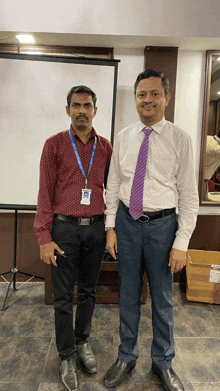 two men are posing for a picture and one has a lanyard around his neck