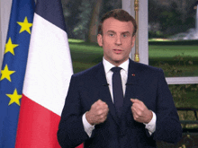 a man in a suit stands in front of a french flag