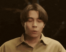 a young man with his eyes closed is wearing a brown shirt
