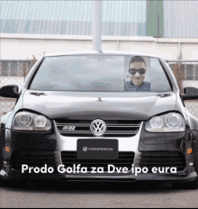 a black volkswagen with a picture of a man behind the windshield