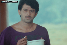 a man in a purple shirt is holding a white container with the hashtag pranay_varma on the bottom right