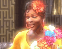 a woman with a flower in her hair wearing a yellow shirt