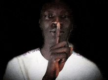 a man in a white shirt is making a shhh gesture
