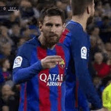 a soccer player wearing a blue and red qatar airways jersey is standing next to another soccer player .