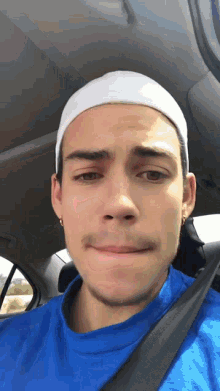 a young man wearing a blue shirt and a white headband looks at the camera
