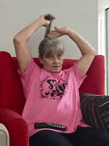 a woman is sitting on a couch wearing a pink t-shirt that says ' girls ' on it