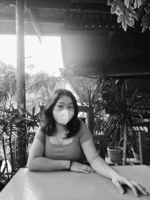 a woman wearing a mask sits at a table in front of a sign that says chab