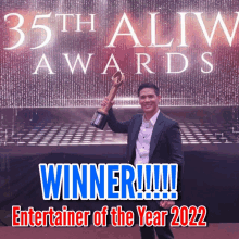 a man holding a trophy in front of a 35th alim awards sign